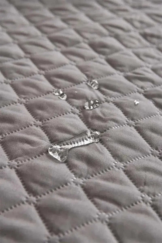 Reusable pet bed mat and furniture protector with water droplets on soft, quilted fabric.