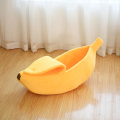 Banana shaped cozy cat nest mat and dog sleeping bag on wooden floor.